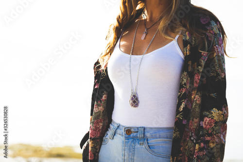 Young boho woman wearing velvet jacket and silver crystal necklace in bright sun light on sunny day