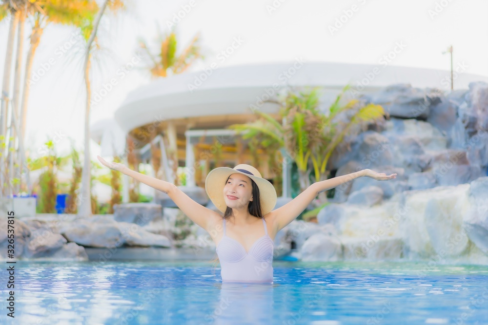 Portrait beautiful young asian woman happy smile relax around outdoor swimming pool in hotel resort