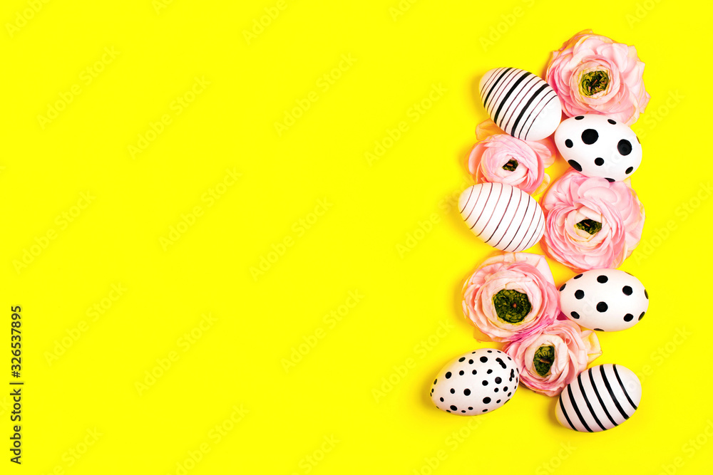 Fototapeta premium Creative graphic hand-painted eggs and ranunculus flowers on bright yellow background. Easter concept.