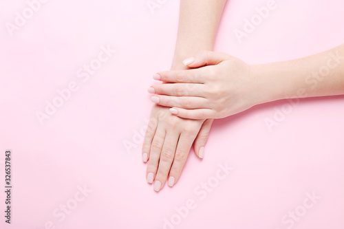 Woman's hands with beautiful manicure on pink background. Hands spa concept