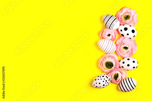 Creative graphic hand-painted eggs and ranunculus flowers on bright yellow background. Easter concept.