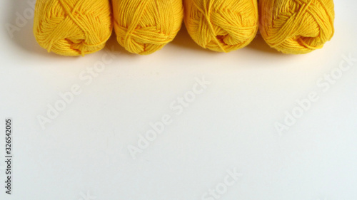 A Line of Skeins of Yellow Yarn on a White Background