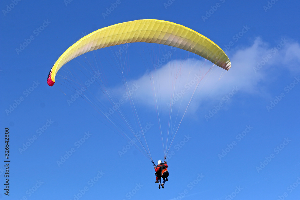 Tandem Paraglider flying wing in a blue sky Tandem Paraglider flying wing in a blue sky