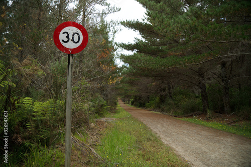 30 km per hour maximum speed warning sign beside an unpaved road in Riverhead Forest, Kumeu, New Zealand.