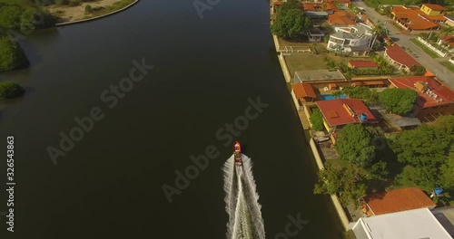 Drone shot following a small red fishing boat on a dark water canal in Higuerote, Venezuela photo
