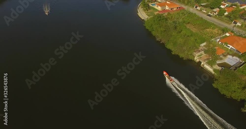 Drone following a small red fishing boat on a canal in Higuerote, Venezuela photo