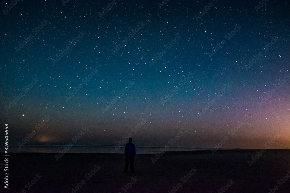 Adventurous man watching the stars on a beach at night. 