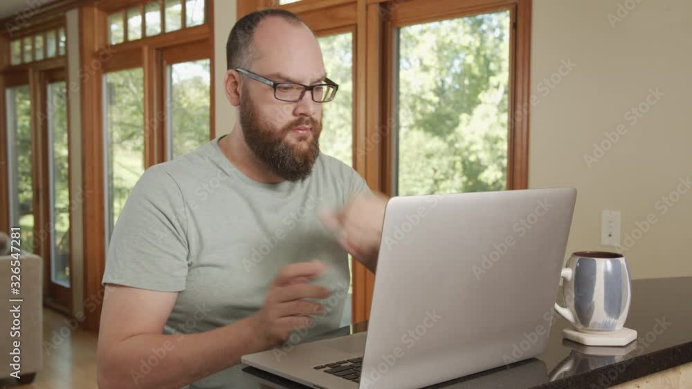 Man in modern home works on laptop computer and drinks coffee while typing Man in modern home works on laptop computer and drinks coffee while typing