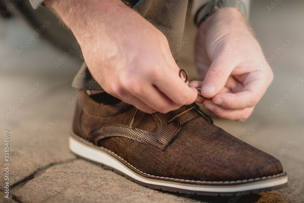 Hombre amarrando las agujetas del zapato café