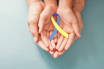 Adult and child hands holding blue and yellow ribbon shaped paper, Down syndrome awareness , World down syndrome day