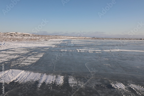 Frozen lake and flat landscape with blue skies, near Arviat, Nunavut