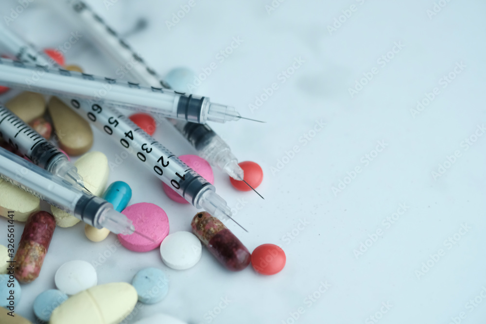 Close up of colored pills and syringe on table Close up of colored pills and syringe on table