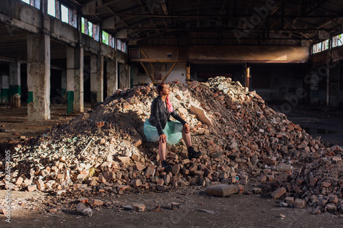 Young girl with pink hair sitting on bricks in a collapsed building