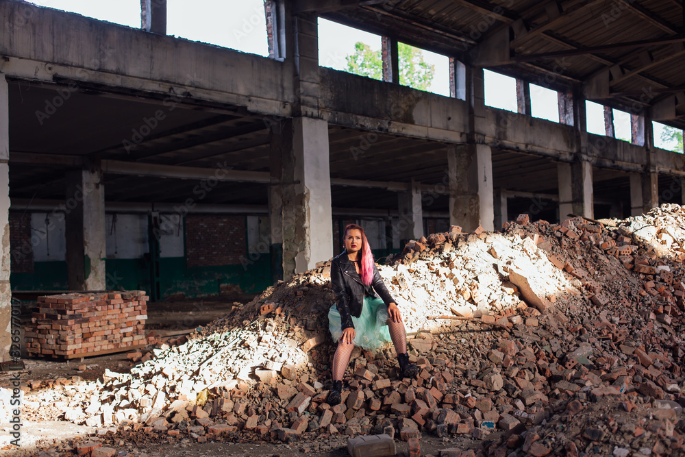 Young girl with pink hair sitting on bricks in a collapsed building Young girl with pink hair sitting on bricks in a collapsed building