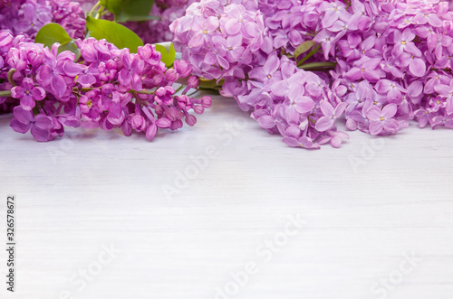Spring lilac flowers as frame on white wooden table background  copy space