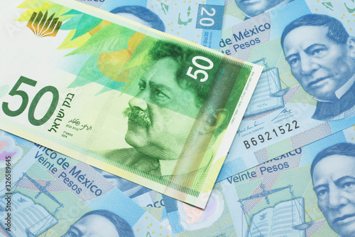 A close up image of a fifty shekel bank note from Israel on a background of Mexican twenty peso bank notes in macro