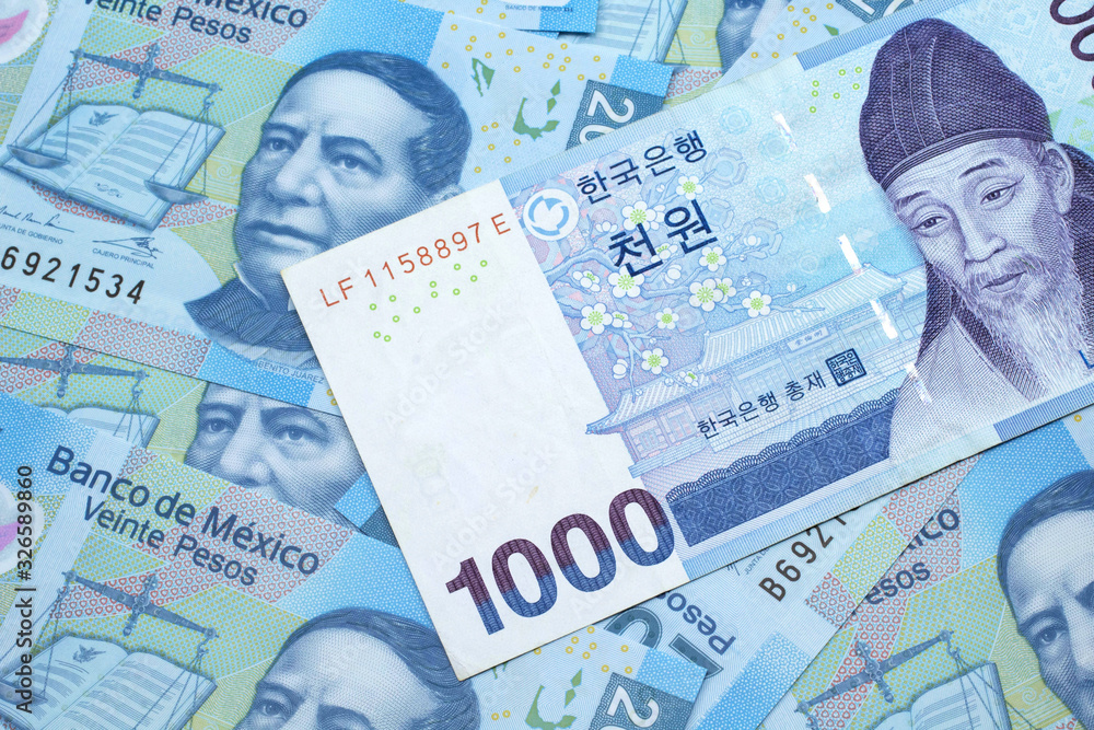 Fototapeta premium A blue South Korean one thousand won bank note close up in macro on a background of Mexican twenty peso bank notes