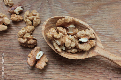 Closeup of peeled walnuts in wooden spoon on wooden background