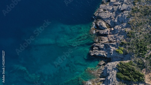 Aerial view of Kotor bay, Lustica peninsula, Montenegro natural landscape. Rocky coastline, azure water surface with foaming waves. Huge stones underwater. © dimabucci