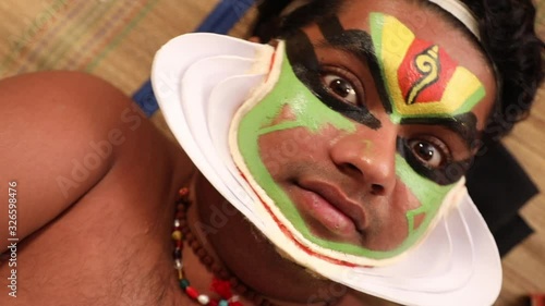 Close up of a Kathakali dancer lying on the chatai and looking upwards.  photo