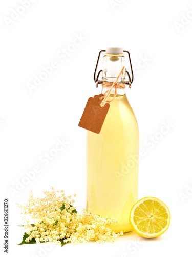 Homemade elderflower syrup in a bottle with flower (Sambucus nigra) and lemon isolated on white background.