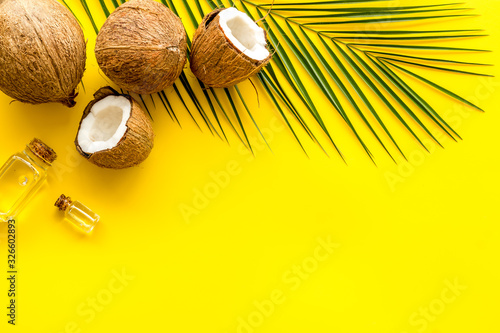 Coconut background with oil on yellow background top-down copy space