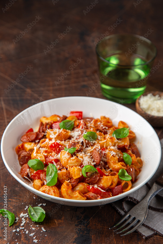 Spicy sausages marinara pasta with parmesan cheese and fresh basil in white bowl Spicy sausages marinara pasta with parmesan cheese and fresh basil in white bowl