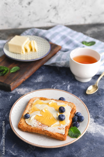 Tasty toasted bread with honey, butter and berries on table