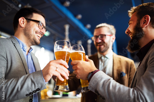 Photography Happy young businessmen drinking beer and talking at pub after work