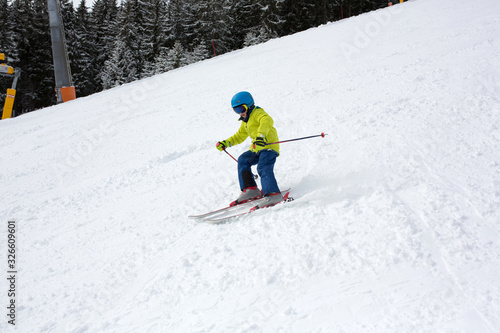 Child, skiing in winter ski resort on a sunny day, enjoying sports in nature