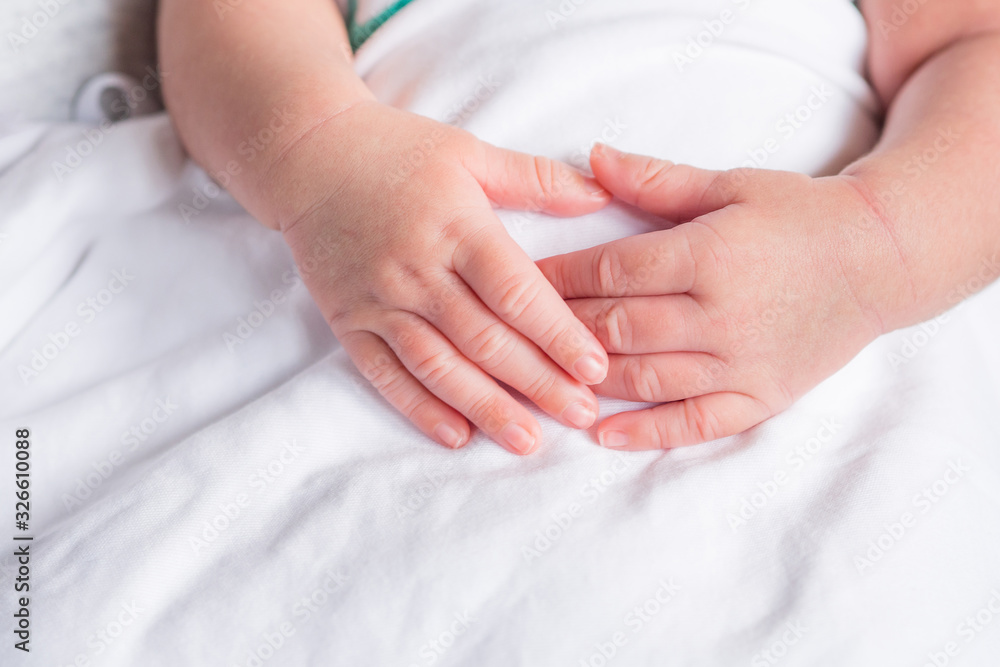 Hands of newborn baby on white cloth with copy space. Close-up of baby hands. Selective focus. Love of family concept Hands of newborn baby on white cloth with copy space. Close-up of baby hands. Selective focus. Love of family concept