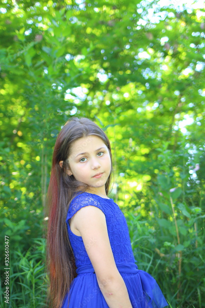  beautiful girl in a blue dress with a bouquet of daisies and a wreath of wildflowers in the summer botanical garden