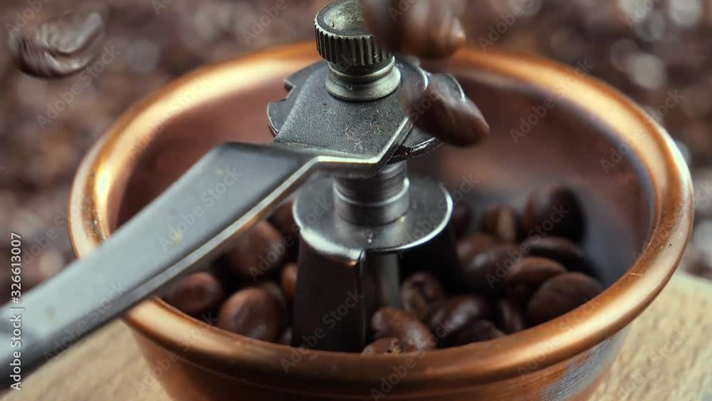 Roasted coffee beans slowly falling into the grinder Roasted coffee beans slowly falling into the grinder