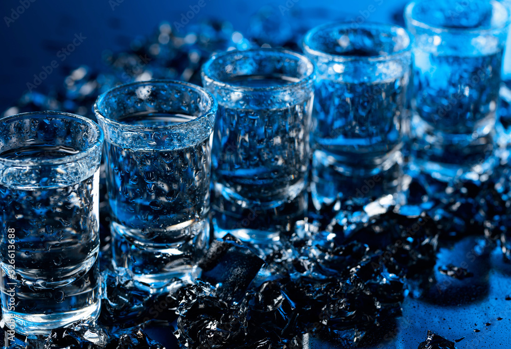 Damp glasses of vodka with ice on a black reflective background. Damp glasses of vodka with ice on a black reflective background.