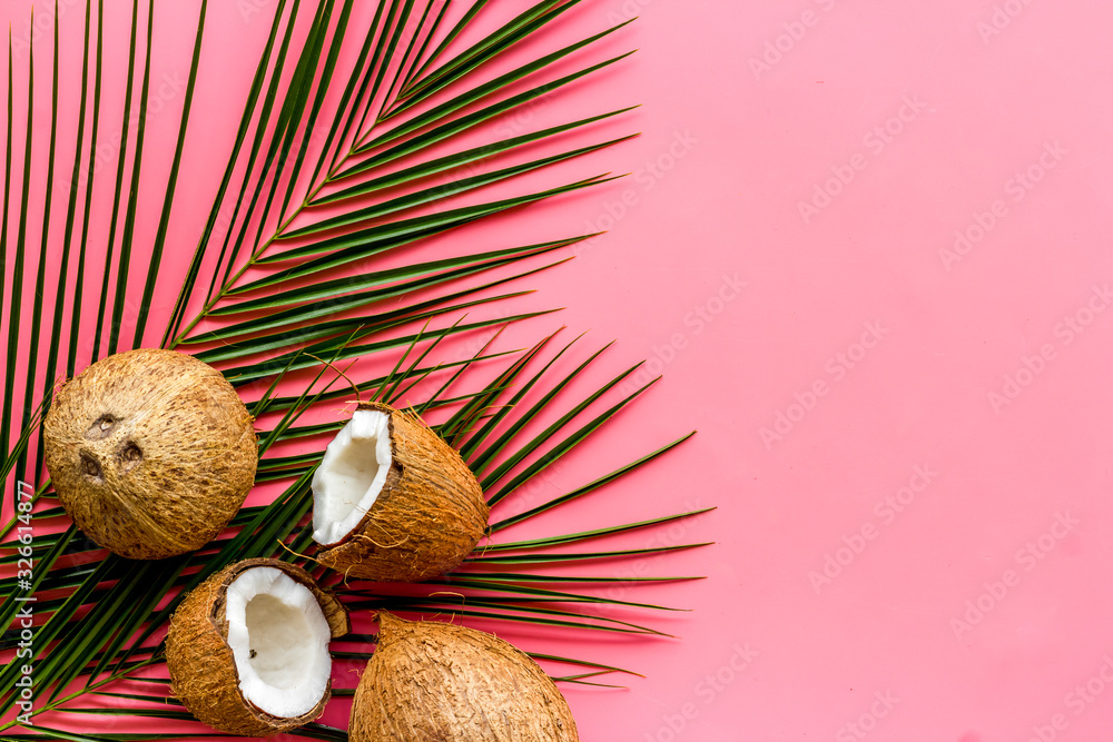 Exotic background with coconuts and palm leaves on pink background top-down frame copy space Exotic background with coconuts and palm leaves on pink background top-down frame copy space