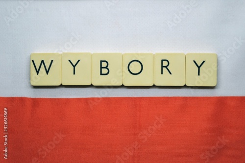 ELECTIONS (polish: wybory) word made from  game tiles with letters.  Selective focus. Elections in Poland theme. Letters on the background with white and red flag of Poland