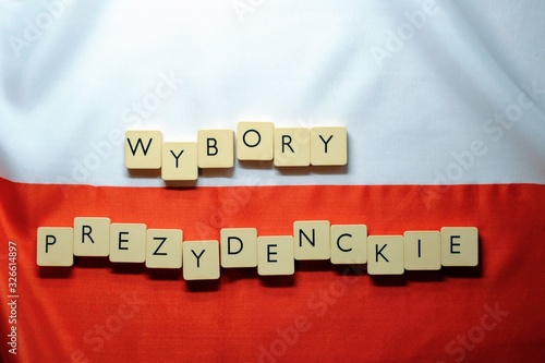 PRESIDENTAL ELECTIONS (polish: wybory prezydenckie) word made from game tiles with letters. Selective focus. Elections in Poland theme. Letters on the background with white and red flag of Poland