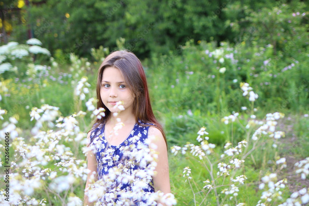 young beautiful girl in blue romper in floral print in the summer garden. Holidays and entertainment young beautiful girl in blue romper in floral print in the summer garden. Holidays and entertainment