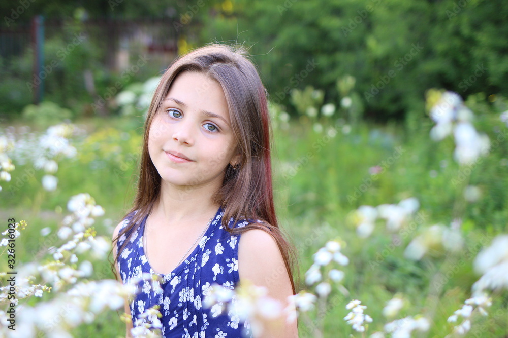 young beautiful girl in blue romper in floral print in the summer garden. Holidays and entertainment young beautiful girl in blue romper in floral print in the summer garden. Holidays and entertainment