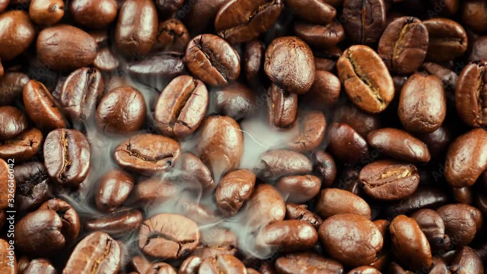 Black coffee beans are fried in a skillet with smoke. Black coffee beans are fried in a skillet with smoke.