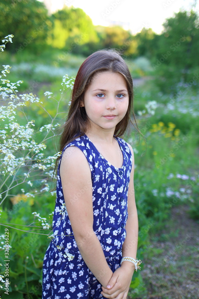 young beautiful girl in blue romper in floral print in the summer garden. Holidays and entertainment young beautiful girl in blue romper in floral print in the summer garden. Holidays and entertainment