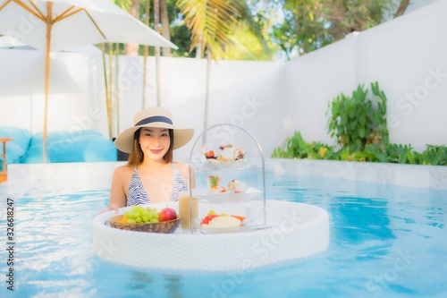 Portrait beautiful young asian woman enjoy with afternoon tea or breakfast floating on swimming pool