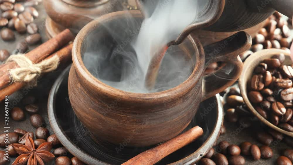 Hot coffee is poured from the ladle into the cup Hot coffee is poured from the ladle into the cup