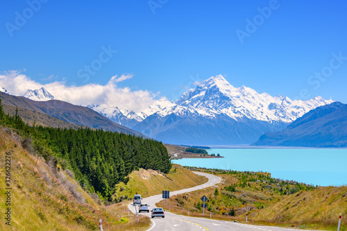 The road curves along Lake Pukaki and Mount Cook on a clear day at Peter's Lookout in the South Island of New Zealand.