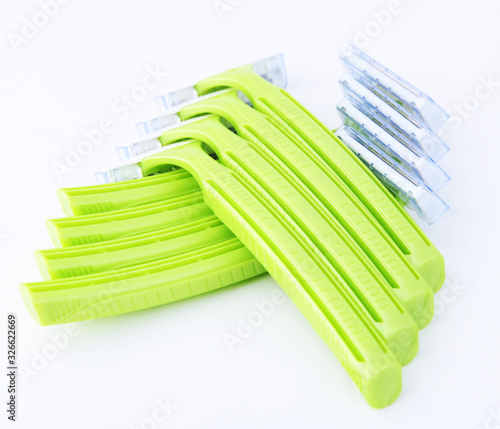 Disposable green plastic razor on a white background.Safe shaving with a sharp razor of female skin. Hair removal from the legs and face. Body care and beauty of a woman.