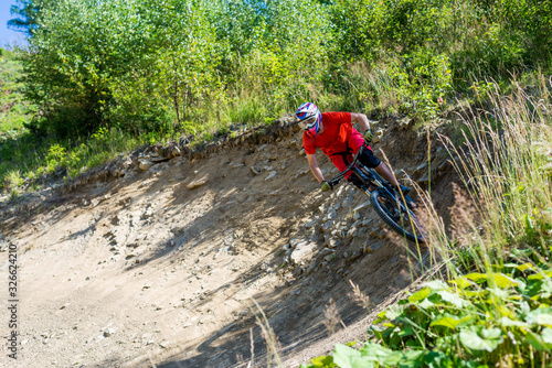 A rider on a mountain bike and in full-face helmet rides on stones.