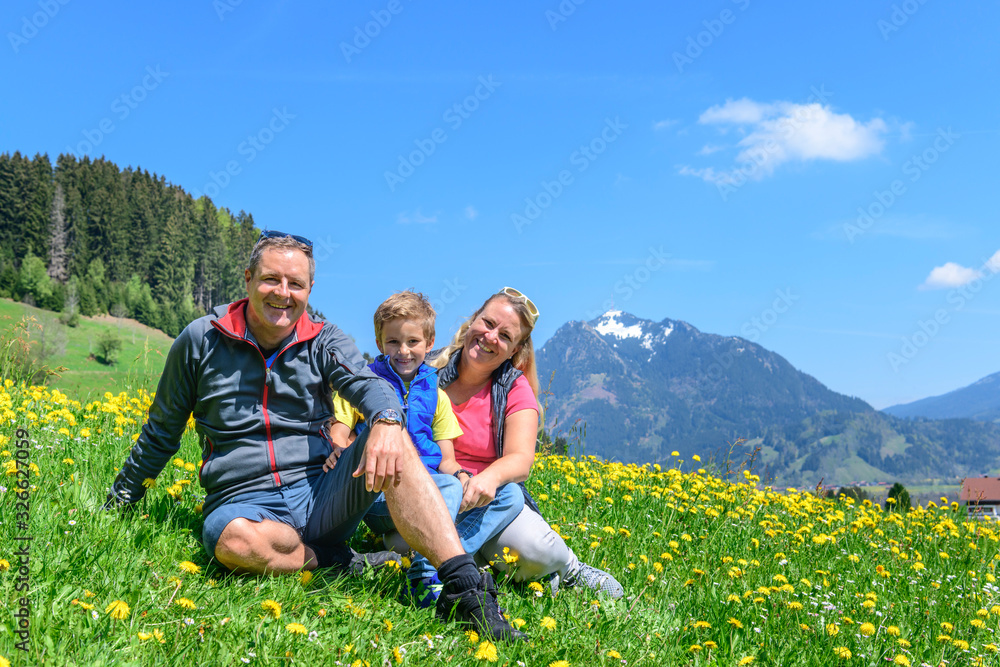 Glückliche Familie sitzt auf einer Wiese im Allgäu Glückliche Familie sitzt auf einer Wiese im Allgäu
