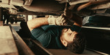 Mechanic under car during repair in workshop