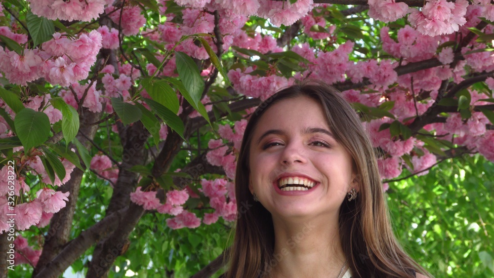 Young girl with beautiful make-up stands under a tree with bright pink sakura flowers Young girl with beautiful make-up stands under a tree with bright pink sakura flowers