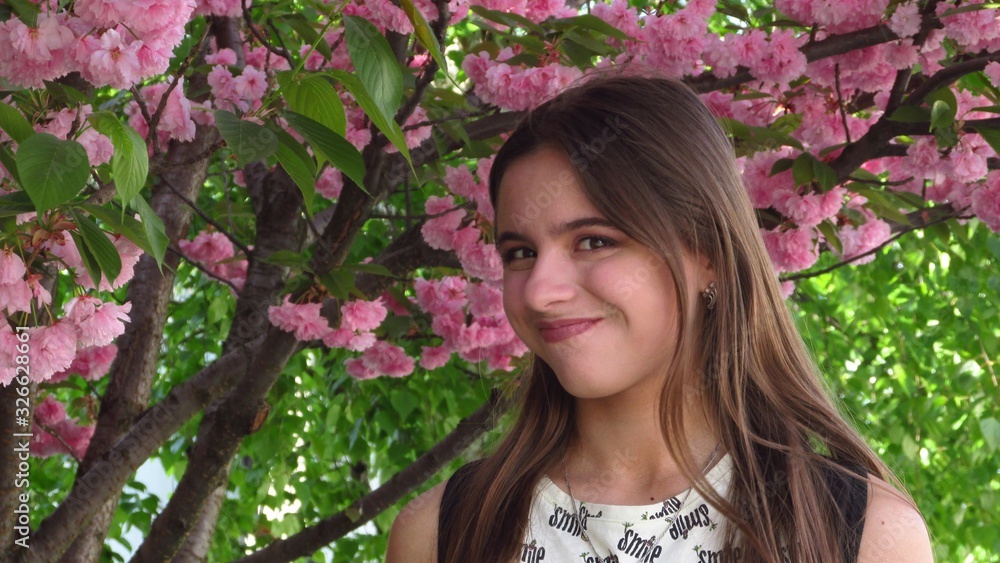 Young girl with beautiful make-up stands under a tree with bright pink sakura flowers Young girl with beautiful make-up stands under a tree with bright pink sakura flowers